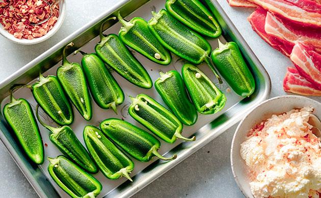 Разрезанные вдоль перцы халапеньо на противне с пергаментом